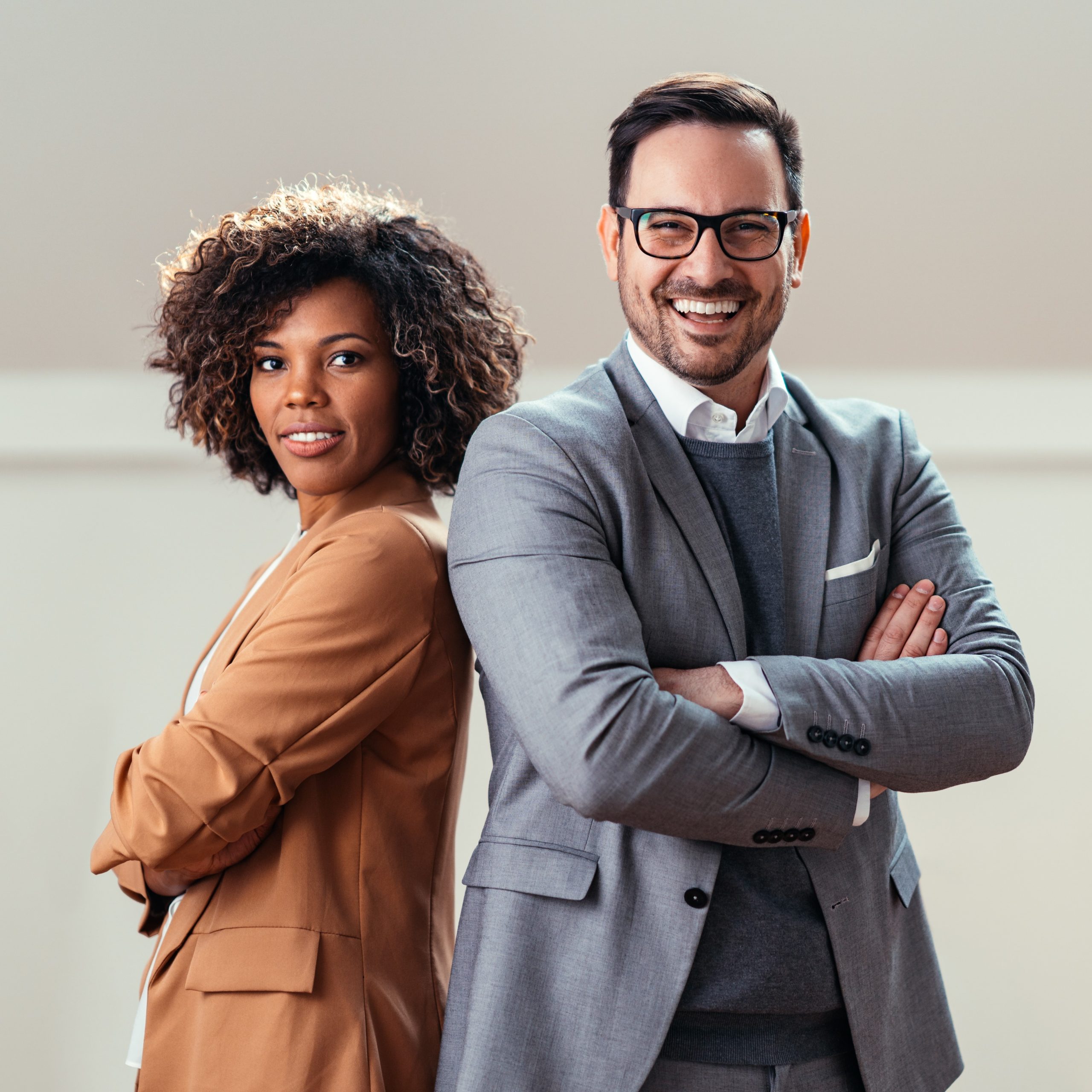 Portrait of cheerful multi ethnic business couple wearing suit and looking at camera with lot of copy space on right side